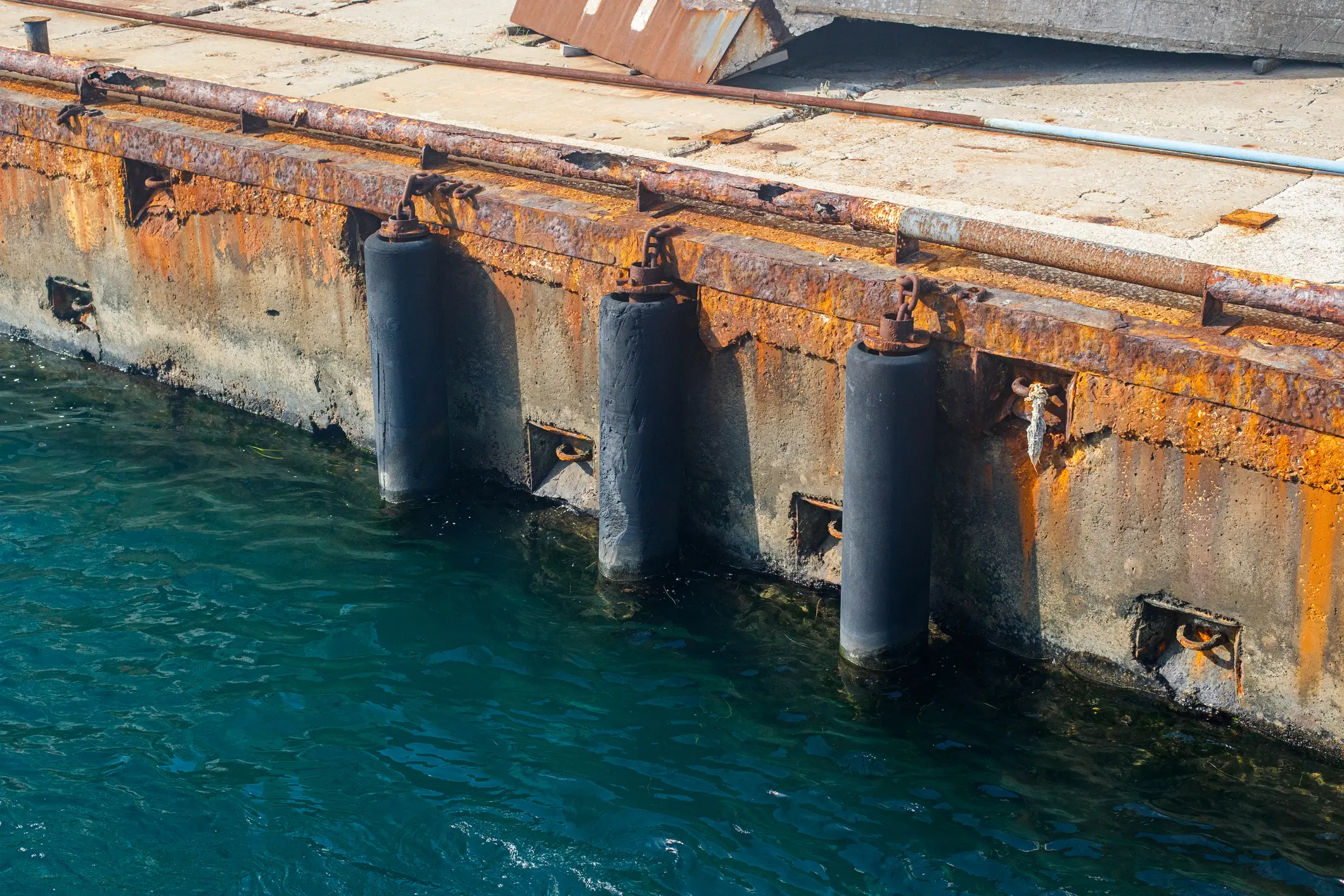 Old rubber pipe mooring bumpers on sea pier in seaport
